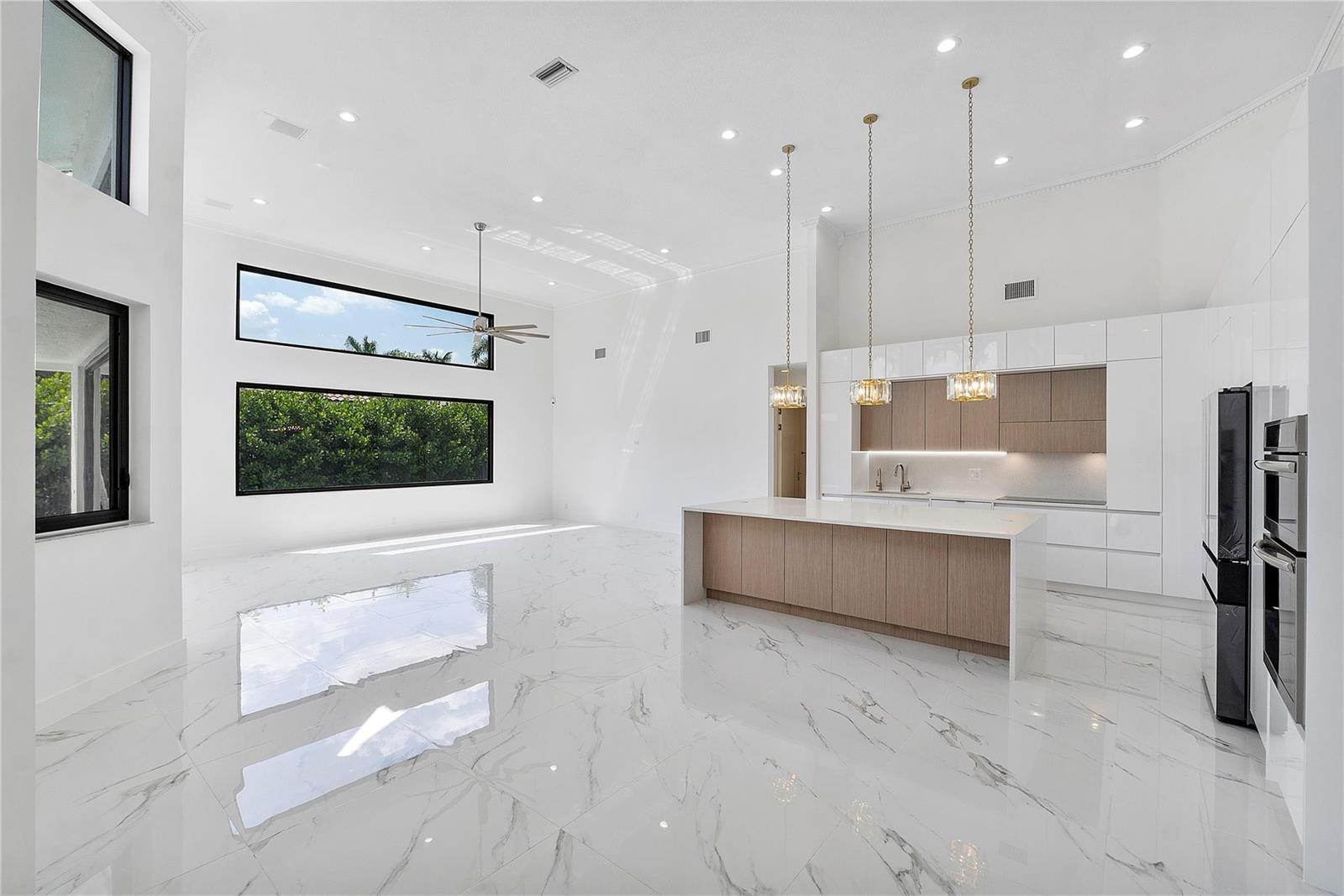 A modern open-concept kitchen and living area with white marble floors and high ceilings — 410 Sabal Way, Weston FL 33326, WESTON, FL