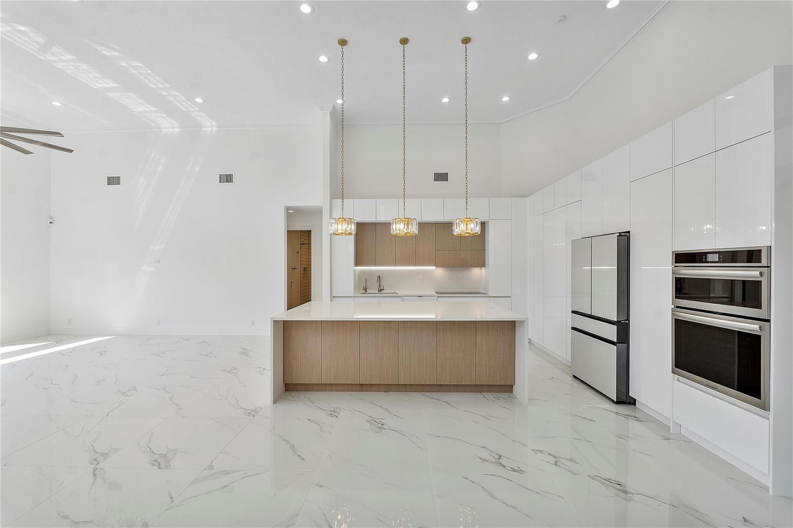 A modern kitchen features a wood-toned island, white cabinetry, and white marble-patterned tile flooring — 410 Sabal Way, Weston FL 33326, WESTON, FL
