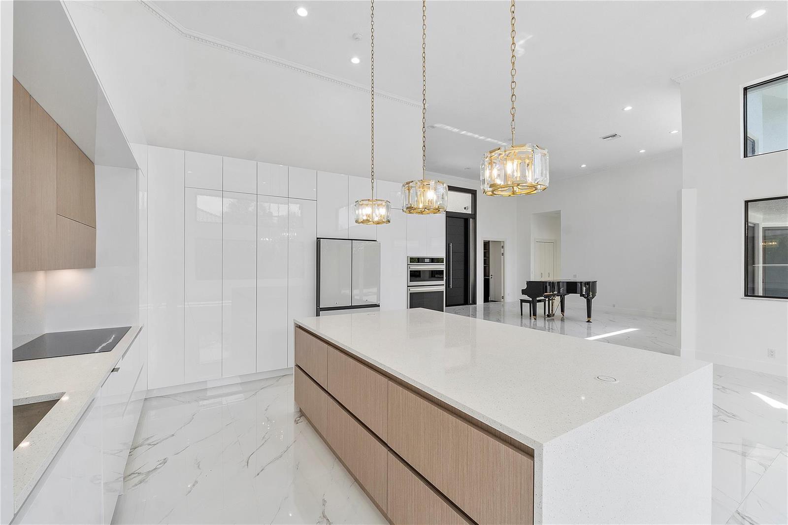 A modern kitchen features white cabinetry, a wood-toned island, and three gold pendant lights — 410 Sabal Way, Weston FL 33326, WESTON, FL