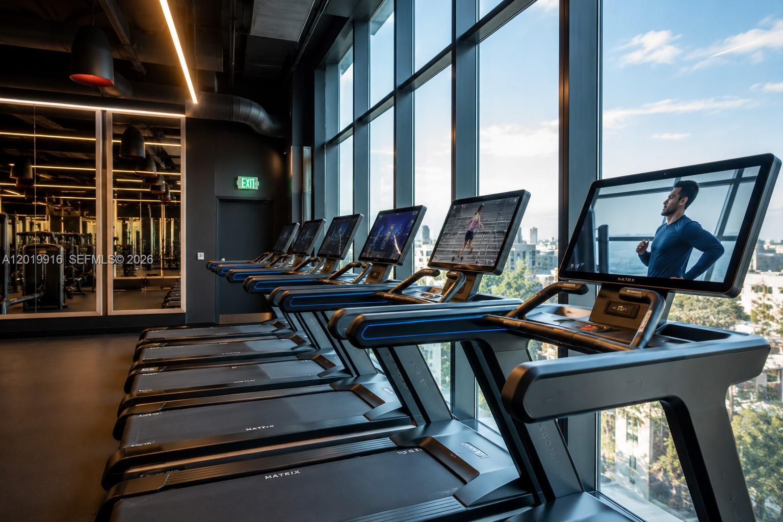 A row of treadmills faces floor-to-ceiling windows overlooking a city skyline in a gym — 20 NE 11 St # 3112B, Miami FL 33132, MIAMI, FL