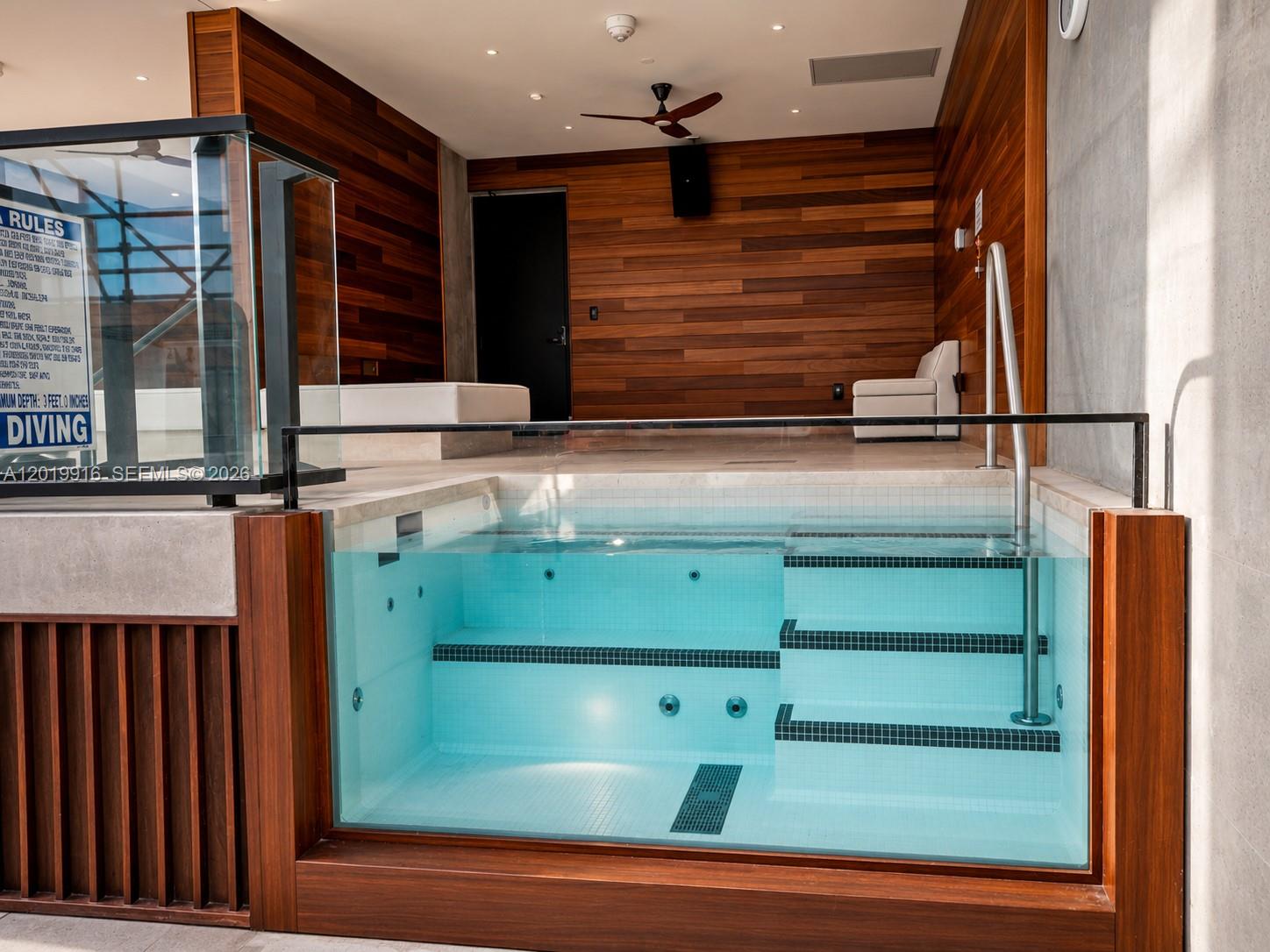 An indoor pool with a glass wall features wood-paneled walls and a tiled seating area — 20 NE 11 St # 3112B, Miami FL 33132, MIAMI, FL