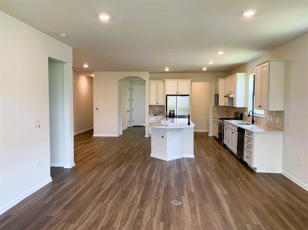 A kitchen with white cabinets, a central island, and wood-look flooring — 12444 GOLDEN SAGE DRIVE, SARASOTA, FL