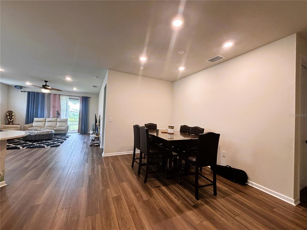 A dining area with a dark table and chairs sits adjacent to an open living room — 12444 GOLDEN SAGE DRIVE, SARASOTA, FL