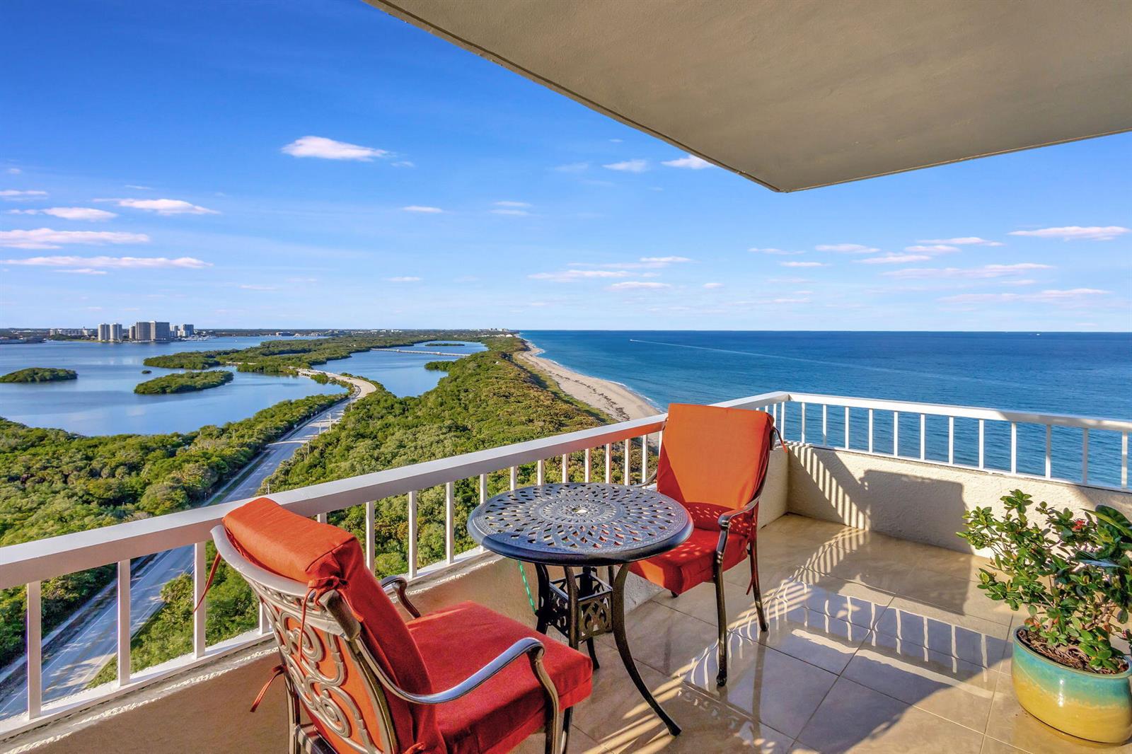 A high-rise balcony features a small table and two chairs overlooking the ocean and coastline — 5550 N Ocean Drive # 21c, Singer Island FL 33404, SINGER ISLAND, FL