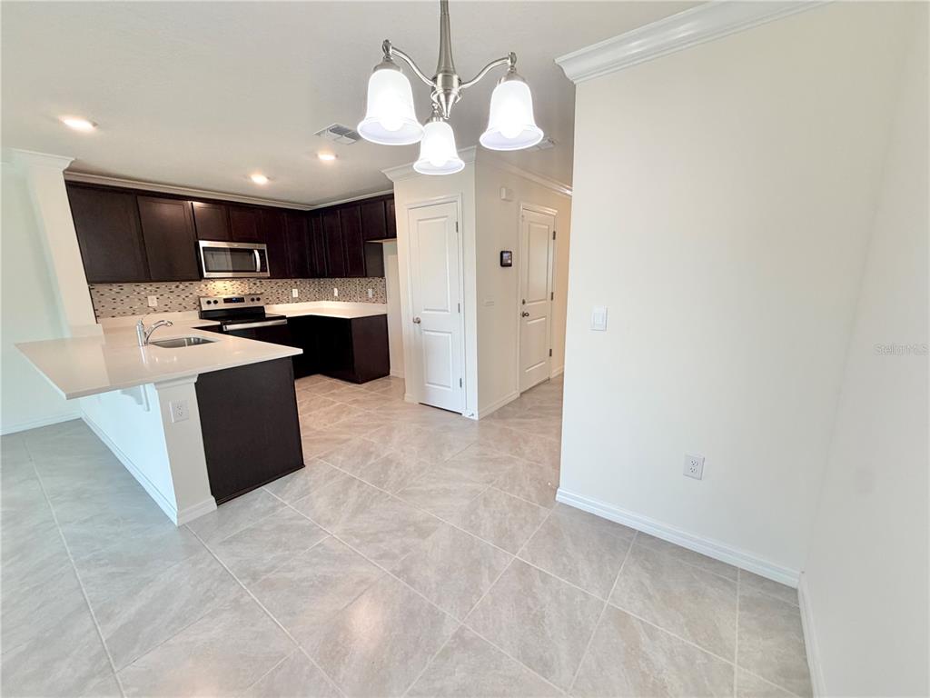 A kitchen features dark wood cabinets, white countertops, a breakfast bar, and tile flooring — 8229 SW 67TH AVENUE, OCALA, FL