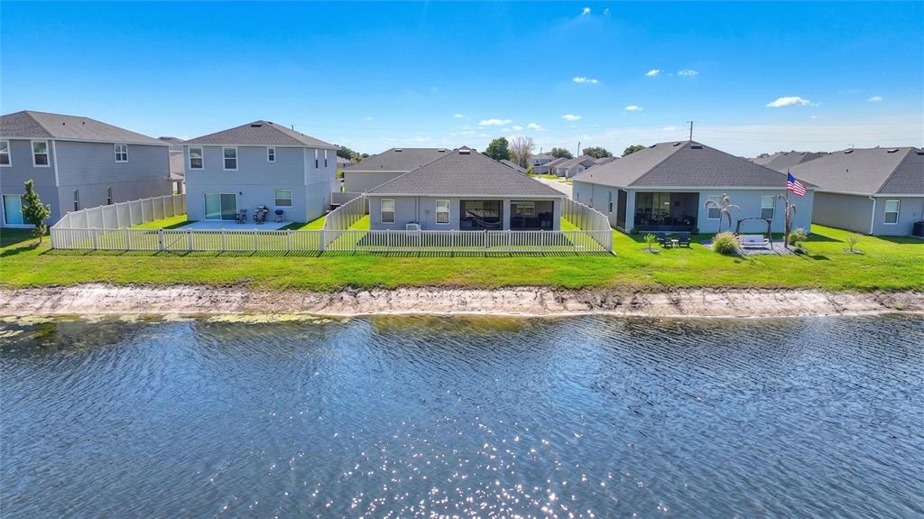 An aerial view shows several suburban houses with fenced backyards situated along a pond — 2852 SAN MARCO WAY, WINTER HAVEN, FL