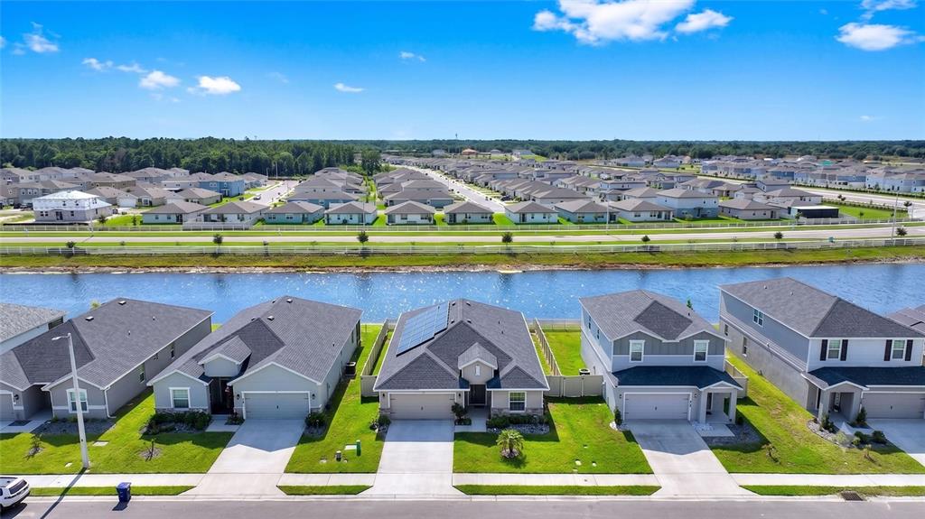 An aerial view shows a row of suburban houses facing a canal and a neighborhood — 2852 SAN MARCO WAY, WINTER HAVEN, FL