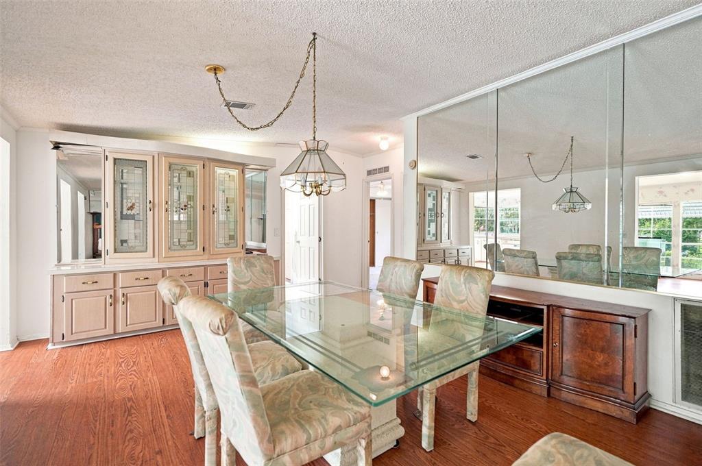 A dining room features a glass-top table, patterned chairs, a built-in hutch, and mirrored walls — 16179 WISCON ROAD, BROOKSVILLE, FL