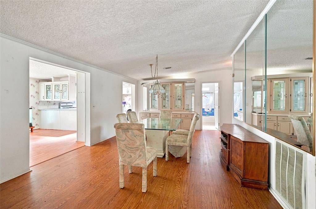 A dining room with wood flooring, a glass table, chairs, and a mirrored wall — 16179 WISCON ROAD, BROOKSVILLE, FL