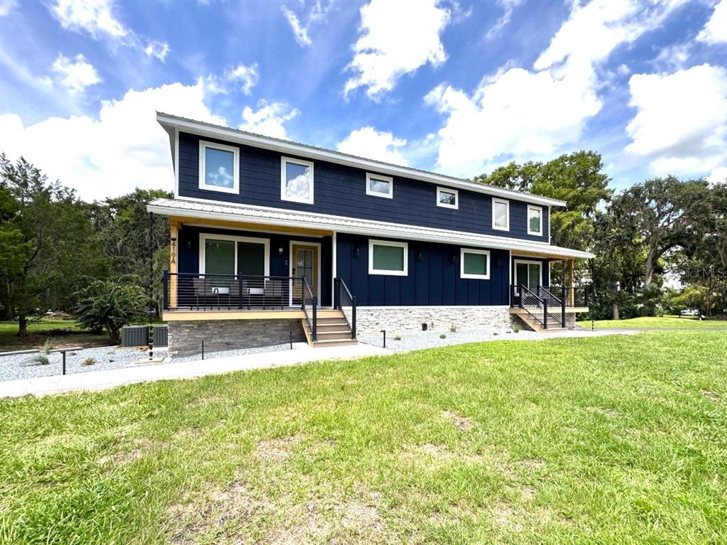 A two-story house with dark blue siding, a stone base, and two front entry porches — 419 N APOPKA AVENUE, INVERNESS, FL