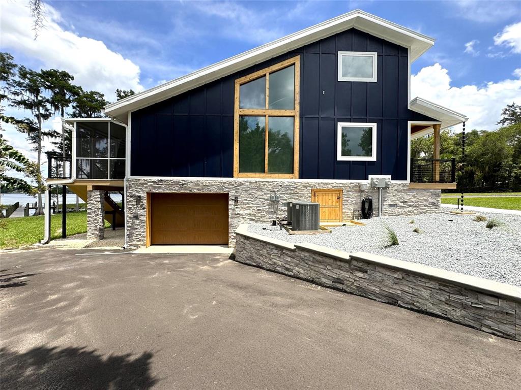 A modern two-story house features dark blue vertical siding, stone veneer, and a garage — 419 N APOPKA AVENUE, INVERNESS, FL