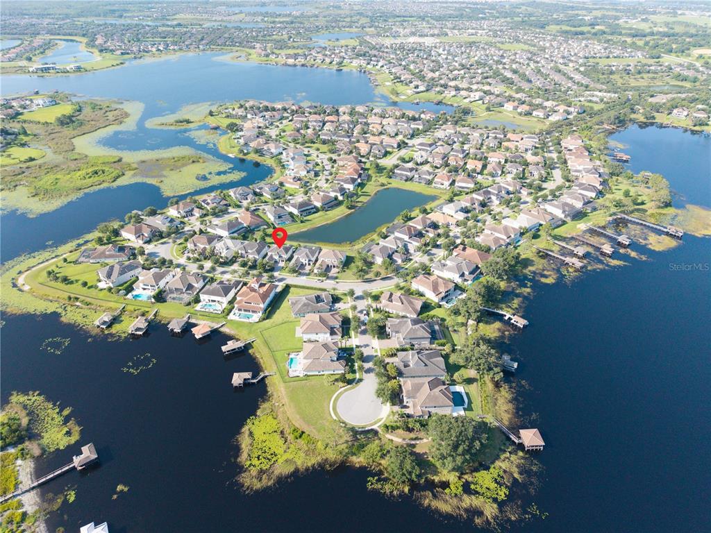 An aerial view shows a residential neighborhood situated on a peninsula surrounded by a lake — 7467 JOHN HANCOCK DRIVE, WINTER GARDEN, FL