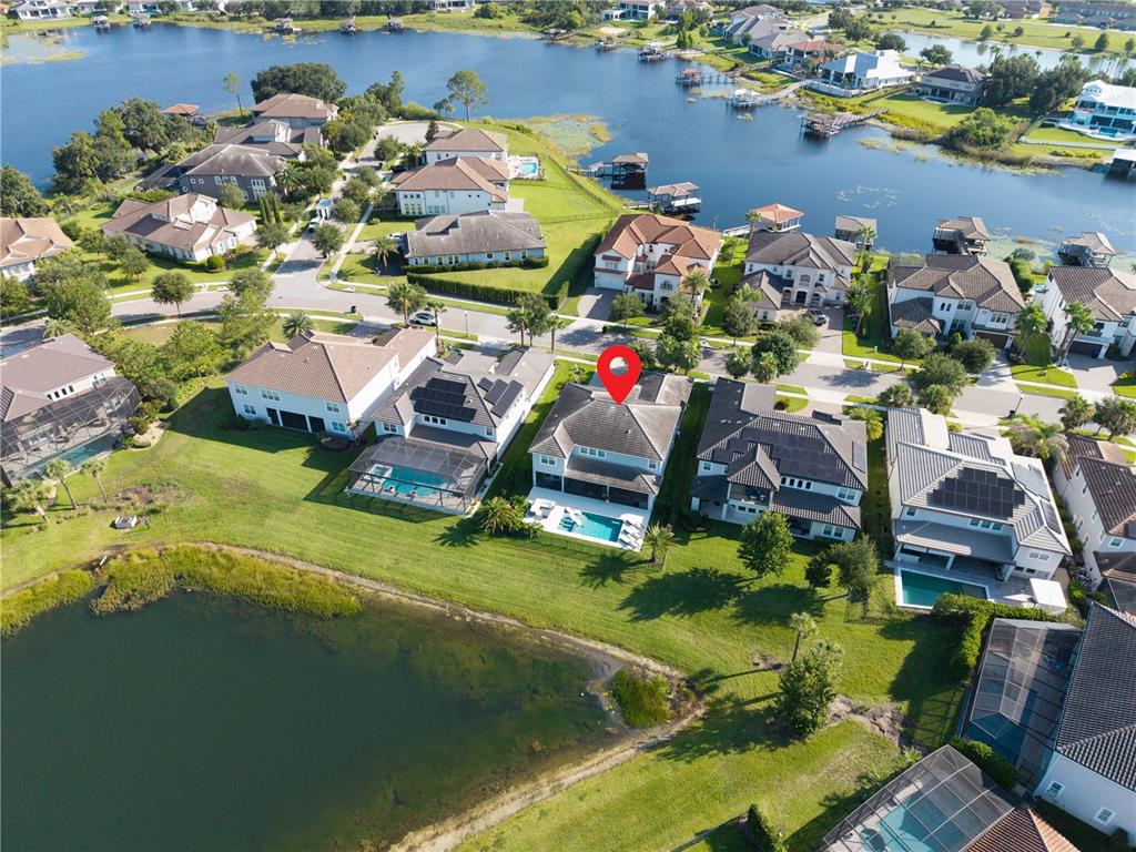 An aerial view shows a residential neighborhood with houses featuring swimming pools near a lake — 7467 JOHN HANCOCK DRIVE, WINTER GARDEN, FL