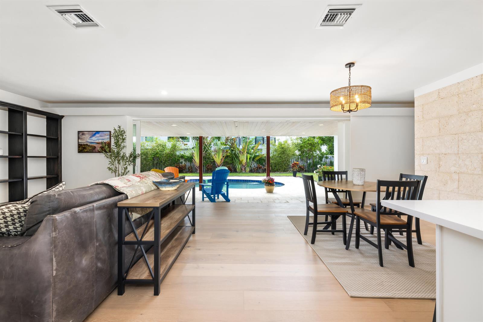 An open-concept living and dining area features light wood floors, a pool, and patio views — 461 Apollo Drive, Juno Beach FL 33408, JUNO BEACH, FL