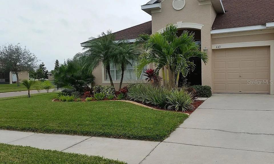 A tan house with a two-car garage and palm trees in the front yard — 443 YORK DALE DRIVE, RUSKIN, FL