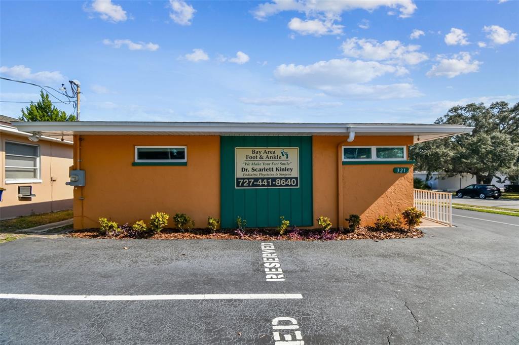 The exterior of a single-story commercial building features orange stucco walls and a green sign — 321 S LINCOLN AVENUE, CLEARWATER, FL