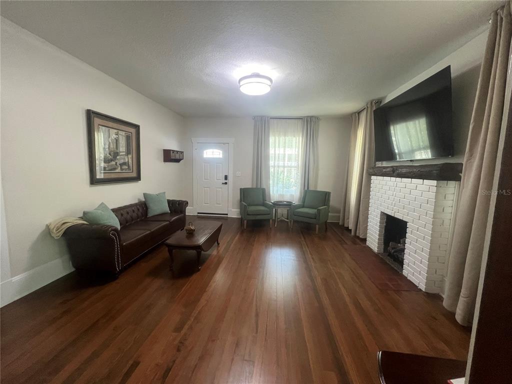 A living room features a brown leather sofa, two armchairs, and a white brick fireplace — 134 N STONE STREET, DELAND, FL