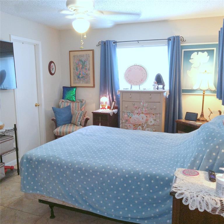 A bedroom features a bed with a blue polka-dot cover, blue curtains, and floral furniture — 7731 MARIAH COURT, ORLANDO, FL