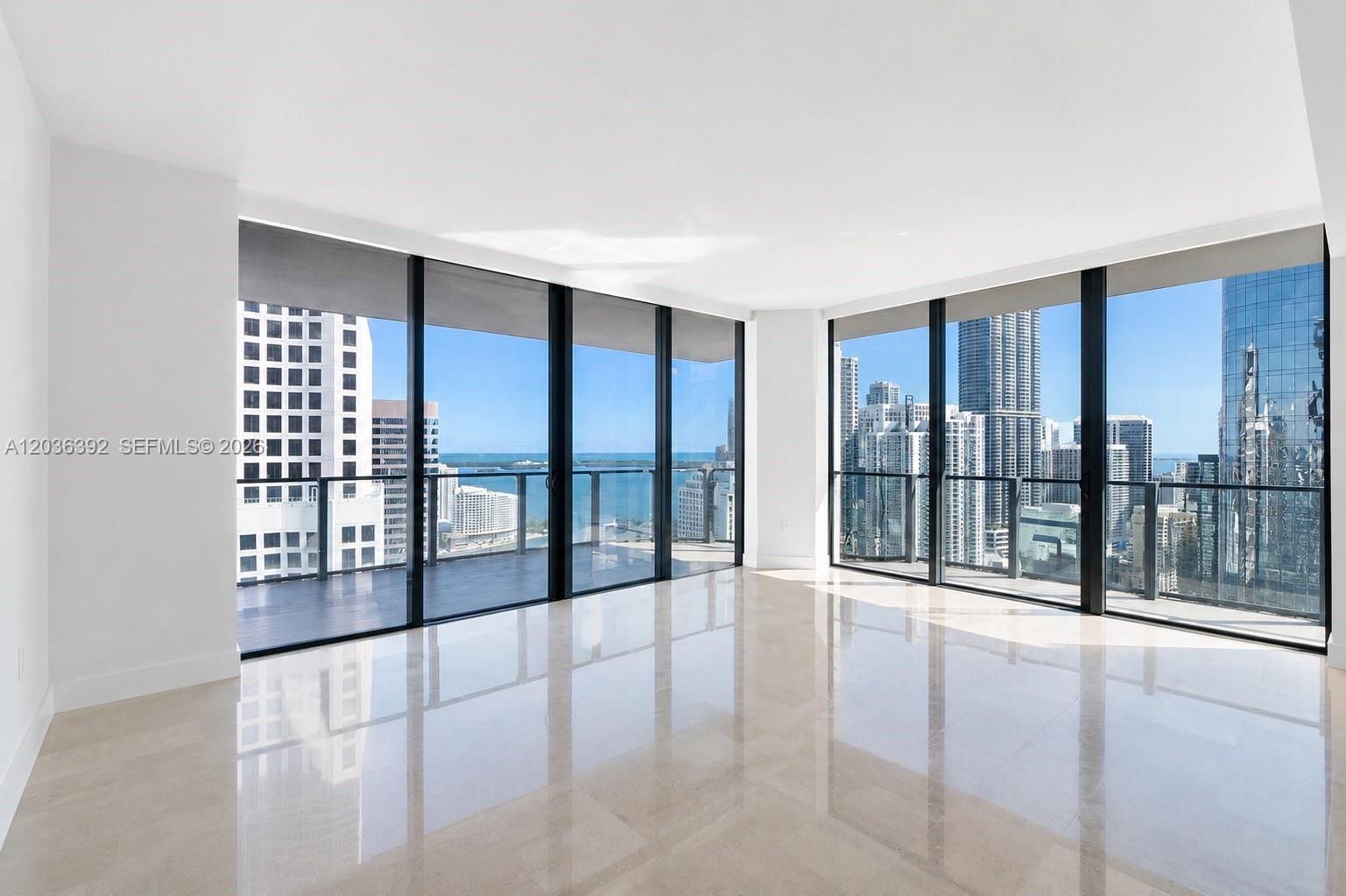 An empty room features floor-to-ceiling windows, light tile flooring, and a balcony overlooking city buildings — 68 SE 6th St # 3301, Miami FL 33131, MIAMI, FL
