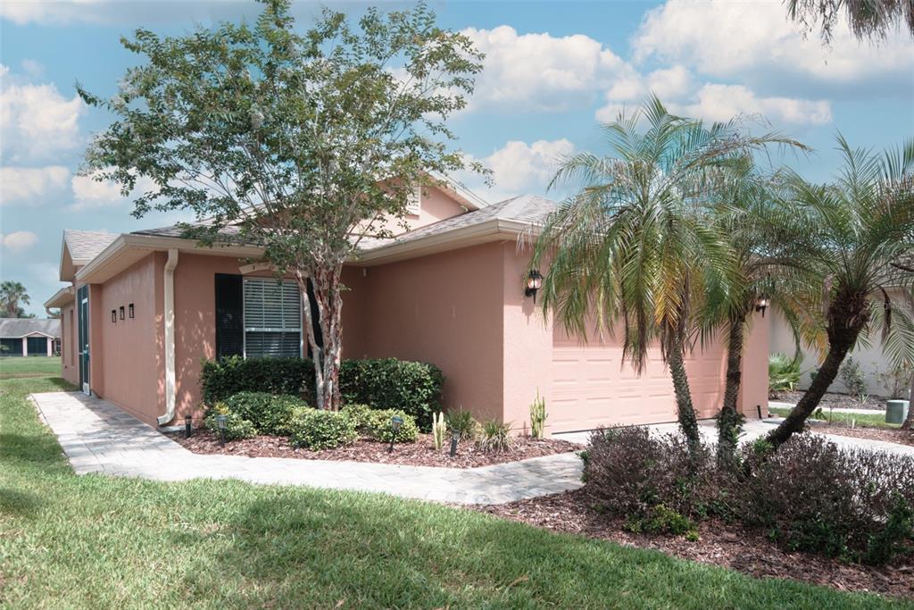 A peach-colored single-story house with a garage, palm trees, and a paved walkway — 601 GRAND CANAL DRIVE, KISSIMMEE, FL