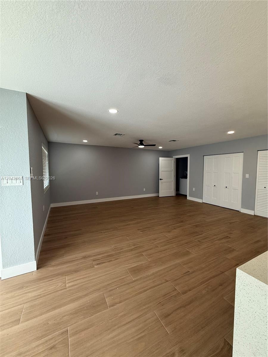 A spacious room features light gray walls, wood-look tile flooring, and recessed ceiling lighting — 311 NW 33rd Ter, Lauderhill FL 33311, LAUDERHILL, FL