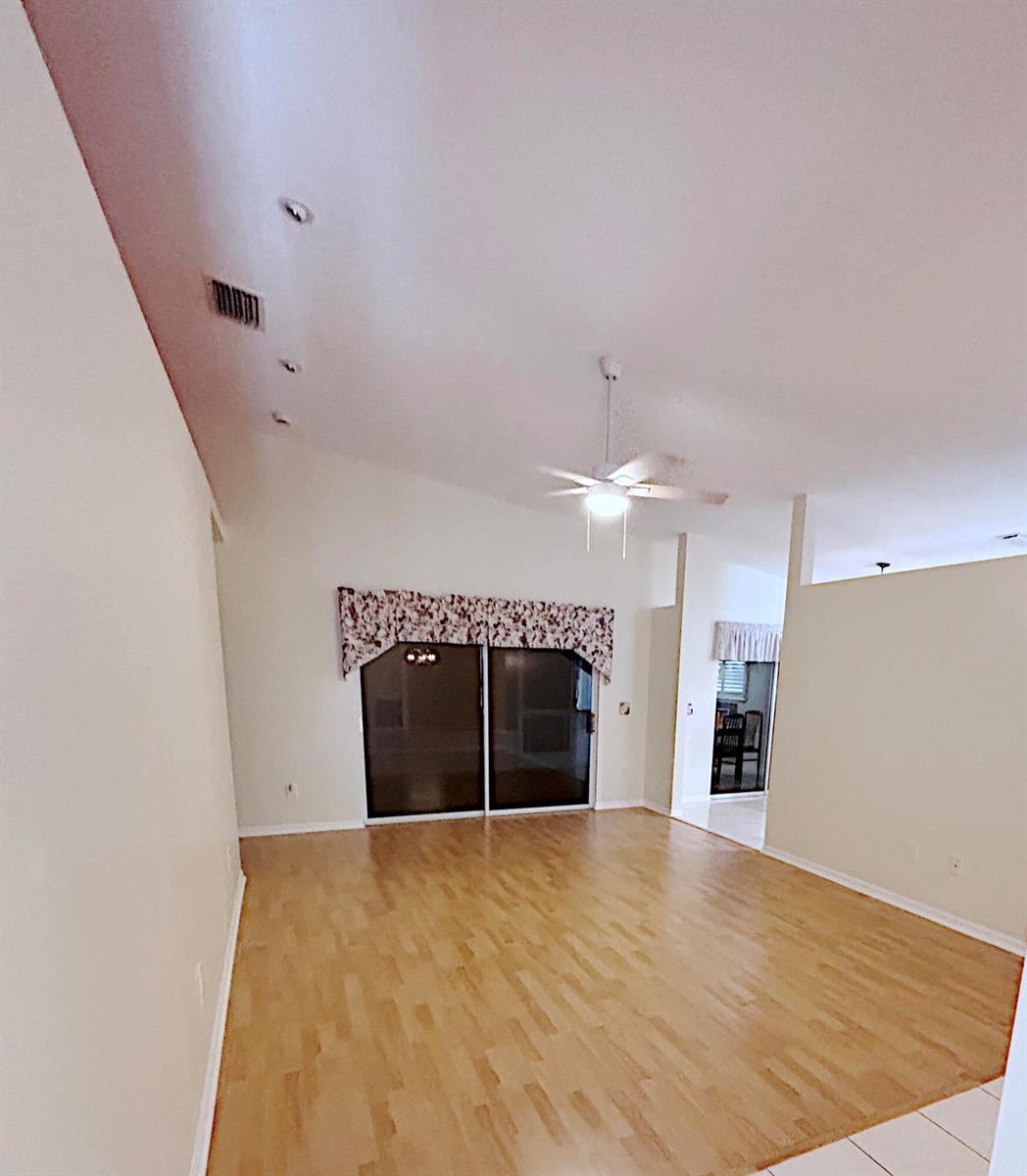 An empty room features light wood flooring, a vaulted ceiling, and sliding glass doors — 14168 Cisne Circle, Fort Pierce FL 34951, FORT PIERCE, FL