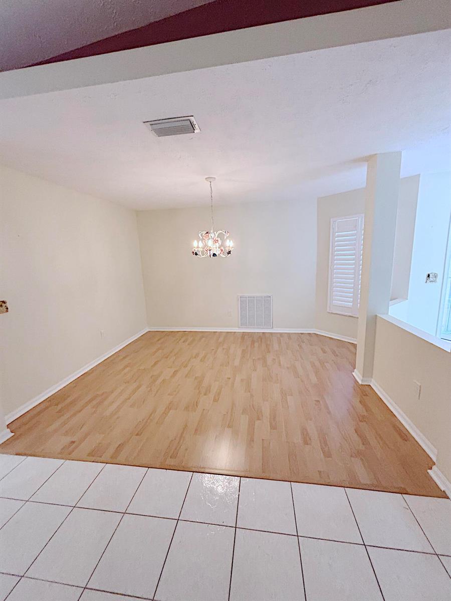 An empty dining room features light wood flooring, a chandelier, and white tile flooring — 14168 Cisne Circle, Fort Pierce FL 34951, FORT PIERCE, FL