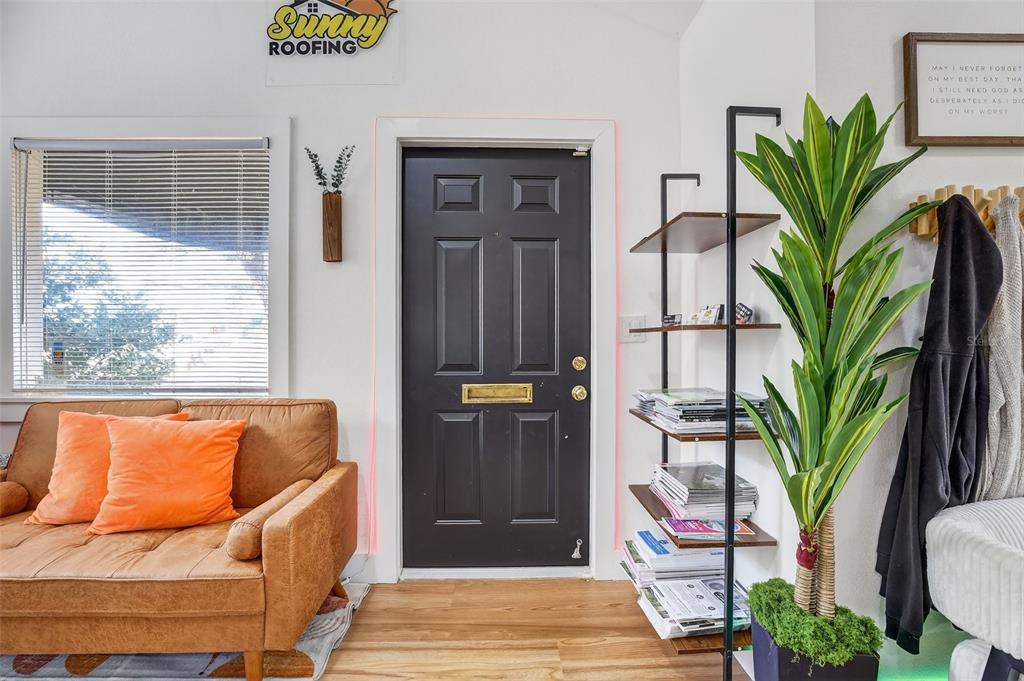 A living room features a black front door, a brown sofa, and a tall potted plant — 1922 HILLCREST STREET, ORLANDO, FL