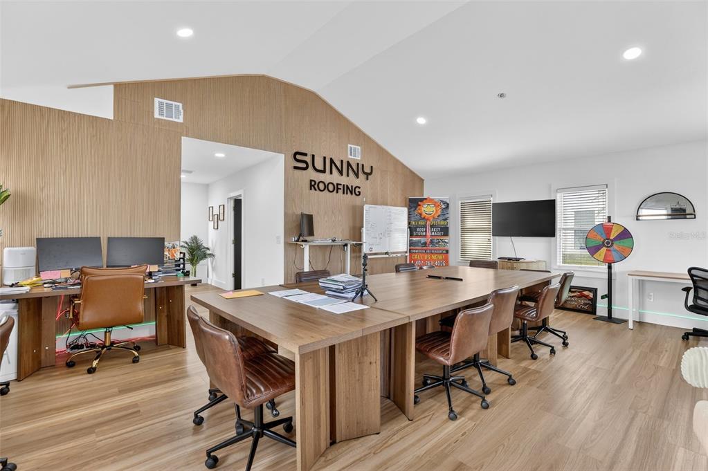 A modern office space features a large wooden conference table, workstations, and wood-paneled accent walls — 1922 HILLCREST STREET, ORLANDO, FL
