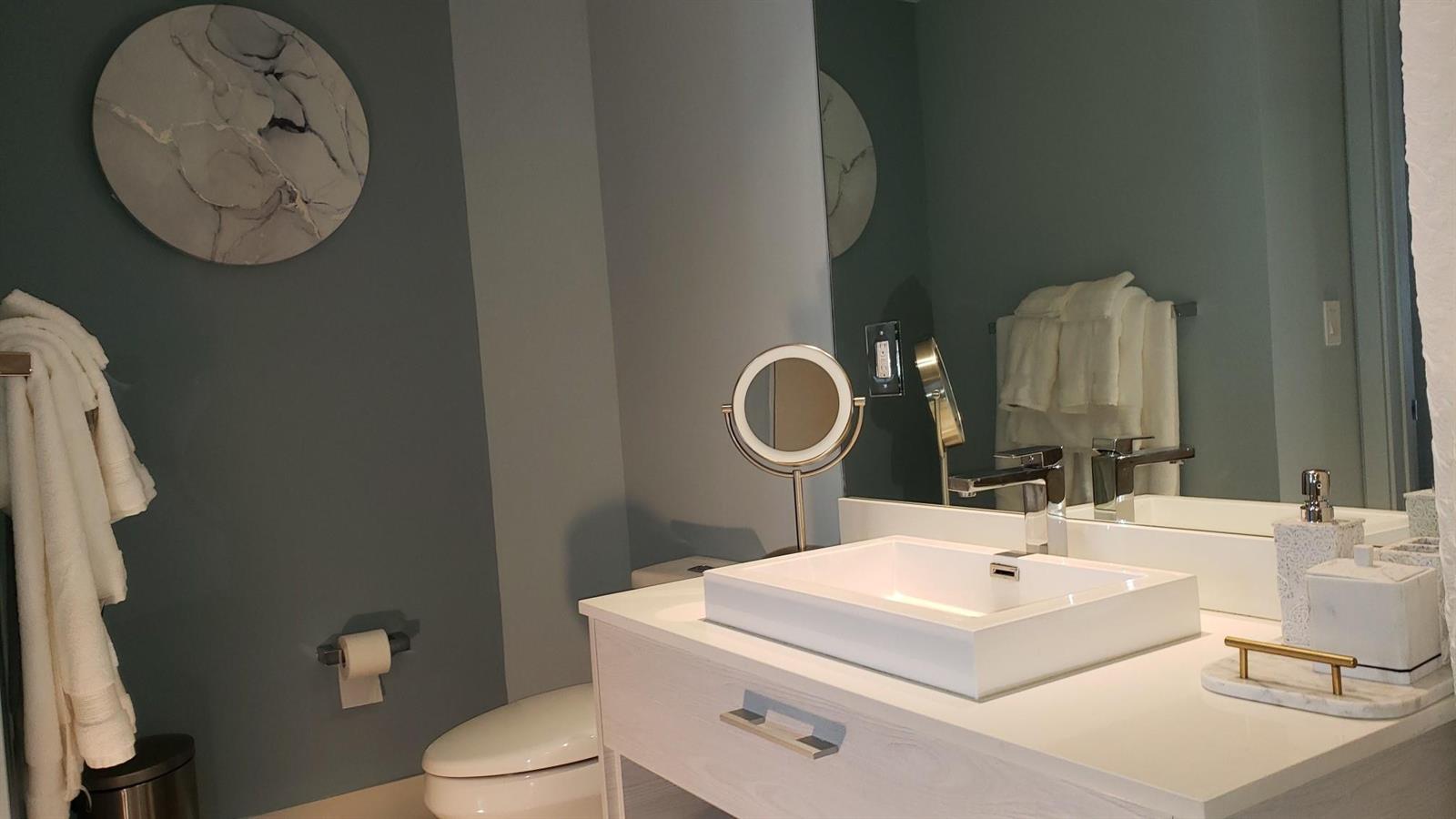 A modern bathroom features a white vessel sink, a marble-patterned wall accent, and blue walls — 55 SW 9th Street # 2210, Miami FL 33130, MIAMI, FL