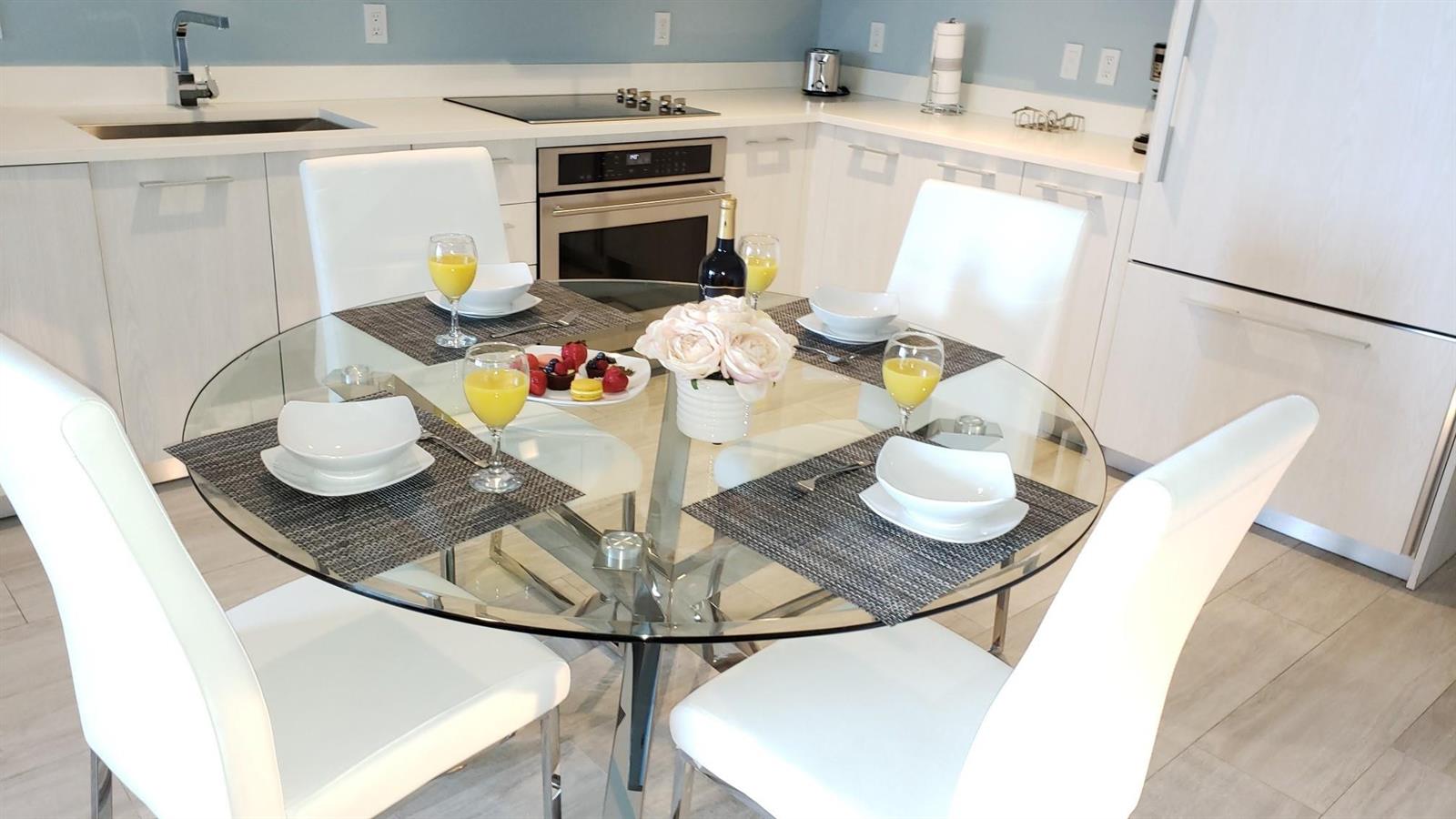 A modern kitchen features a glass dining table with four white chairs and light cabinetry — 55 SW 9th Street # 2210, Miami FL 33130, MIAMI, FL