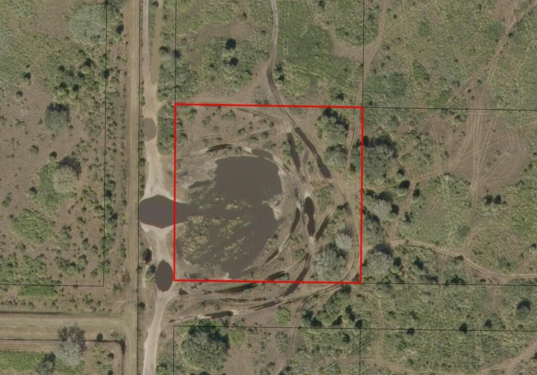 Aerial view of a rural land parcel featuring a large pond and dirt access roads — 0 NW 304th Street, Okeechobee FL 34972, OKEECHOBEE, FL
