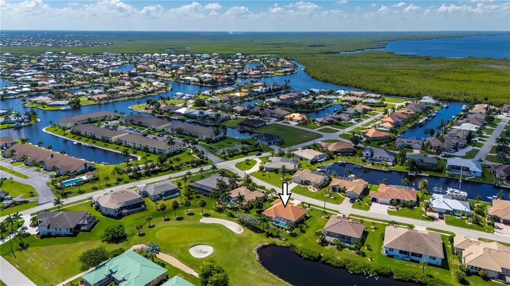 An aerial view shows a residential neighborhood with houses, a golf course, and canals — 1512 SUZI STREET, PUNTA GORDA, FL