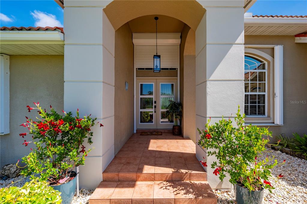 An entryway features wood-look flooring, a console table, a modern pendant light, and arched doorways — 1512 SUZI STREET, PUNTA GORDA, FL