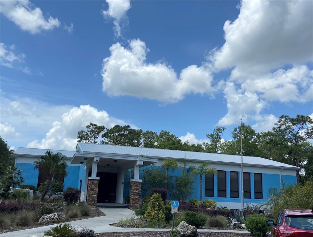 A blue building with a metal roof and stone-accented entryway stands under a cloudy sky — Lot 28 SW 206 CIRCLE, DUNNELLON, FL