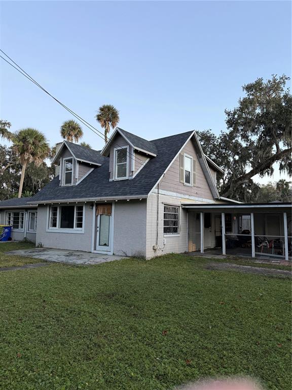A two-story house with a gray exterior, dormer windows, and an attached screened-in porch — 226 WILDWOOD AVENUE, EDGEWATER, FL