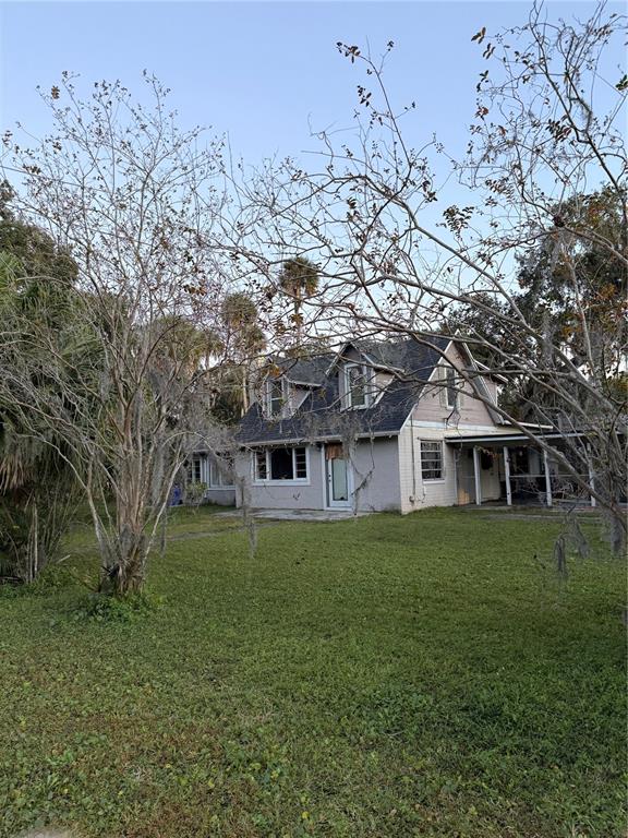 A two-story house with a grey exterior and a dark shingled roof sits on grass — 226 WILDWOOD AVENUE, EDGEWATER, FL