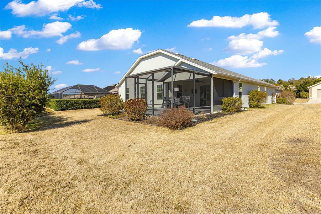 A single-story house with a screened-in lanai sits on a large, dry grassy lot — 11266 SE 170TH LANE, SUMMERFIELD, FL