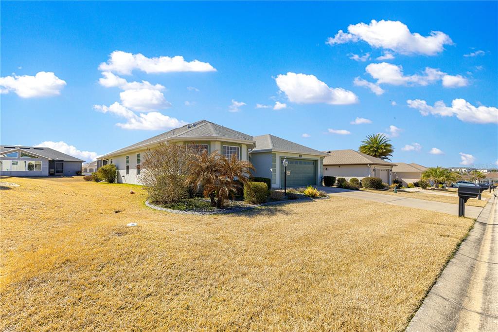 A single-story suburban house with a tan exterior, a two-car garage, and a dry lawn — 11266 SE 170TH LANE, SUMMERFIELD, FL