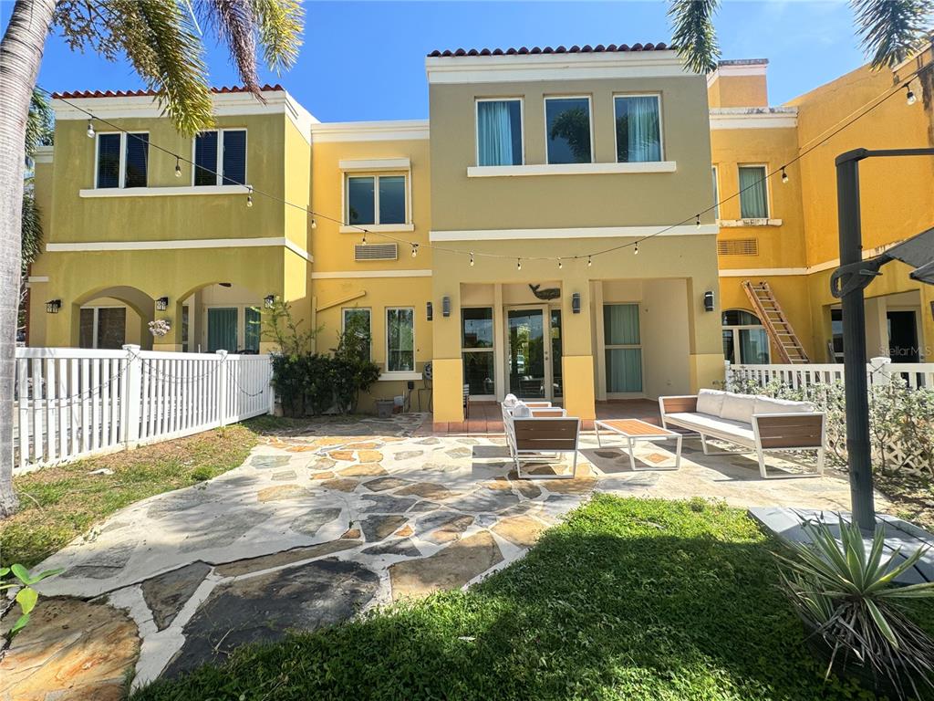 A two-story yellow building features a stone patio with outdoor furniture and string lights — 90 CANDELERO DRIVE UNIT 32, HUMACAO, PR