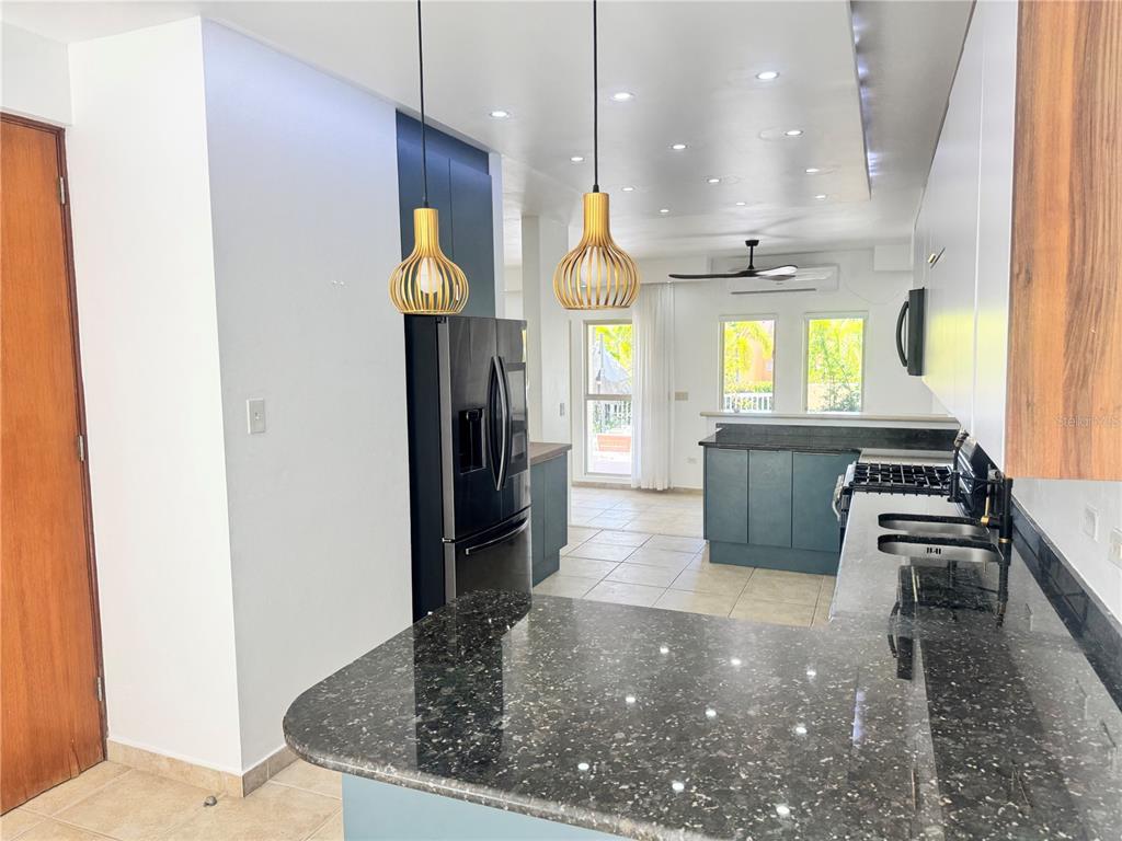 A kitchen features dark granite countertops, blue cabinetry, and two hanging pendant lights — 90 CANDELERO DRIVE UNIT 32, HUMACAO, PR