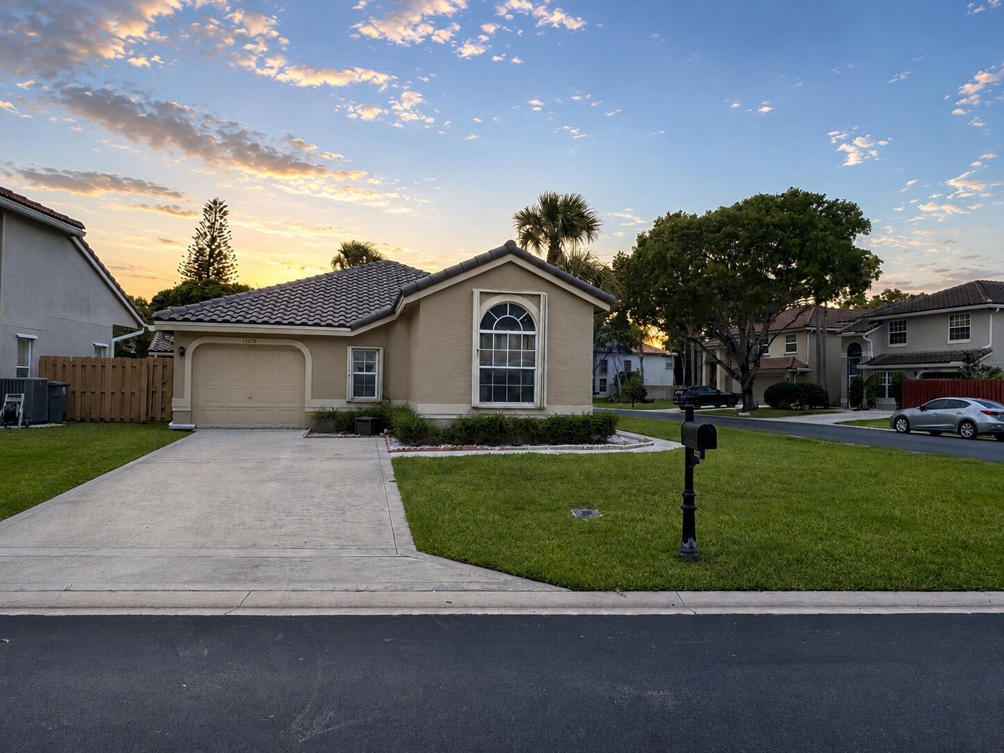 The exterior of a single-story house at dusk features a lawn, patio, and string lights — 10278 Serene Meadow Drive N, Boca Raton FL 33428, BOCA RATON, FL