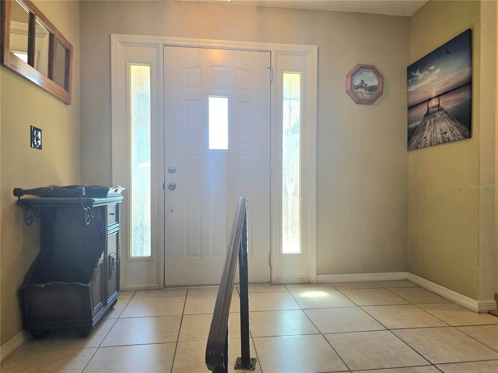 An entryway features a white front door with sidelights, tile flooring, and a handrail — 707 CAMBRIDGE WAY, LAKE WALES, FL