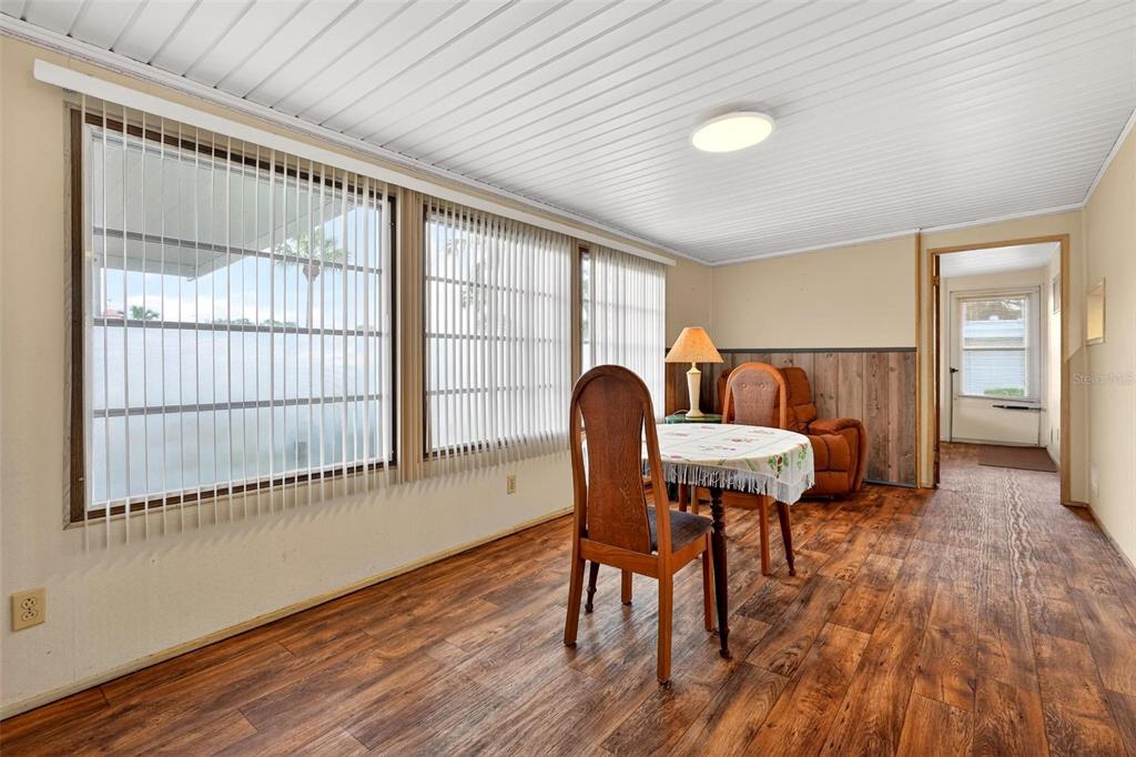 A sunroom features wood-look flooring, wood paneling, vertical blinds, and a small dining set — 11914 HICKORY LANE, TAVARES, FL