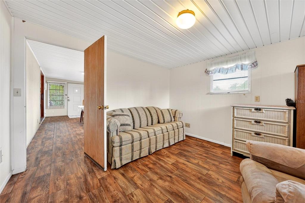 A living room features wood-look flooring, a striped sofa, a dresser, and a ceiling light — 11914 HICKORY LANE, TAVARES, FL