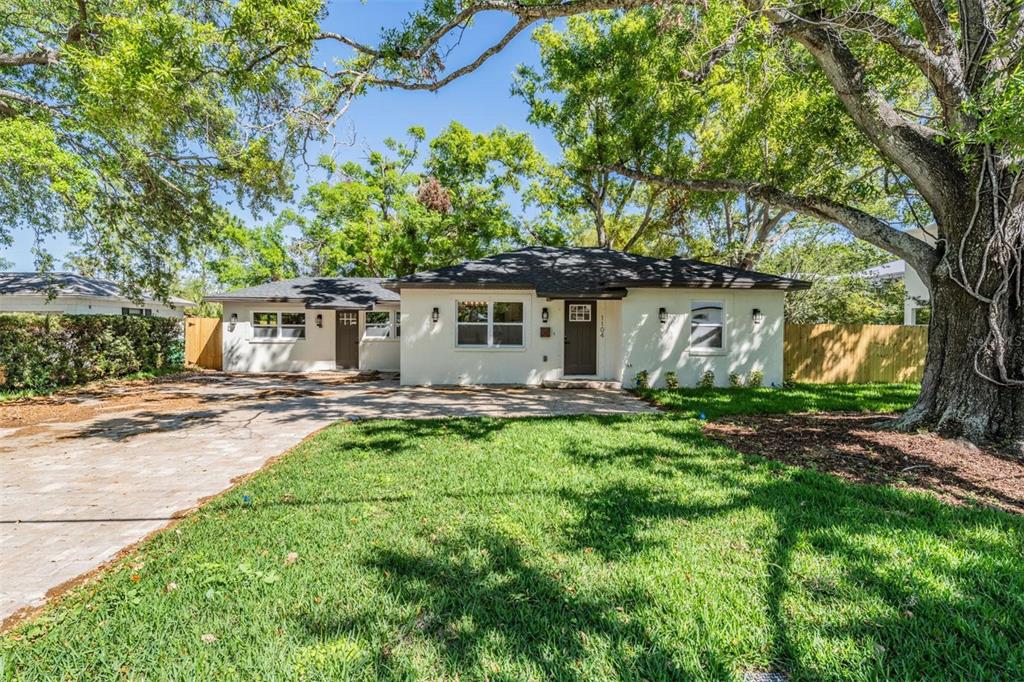 A single-story house with a paved driveway, white exterior, and large trees in the yard — 1104 S LOIS AVENUE, TAMPA, FL