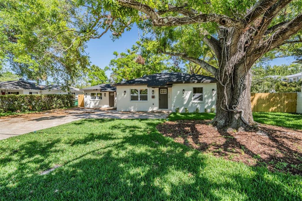 A white single-story house with a dark roof and a large tree in the front yard — 1104 S LOIS AVENUE, TAMPA, FL