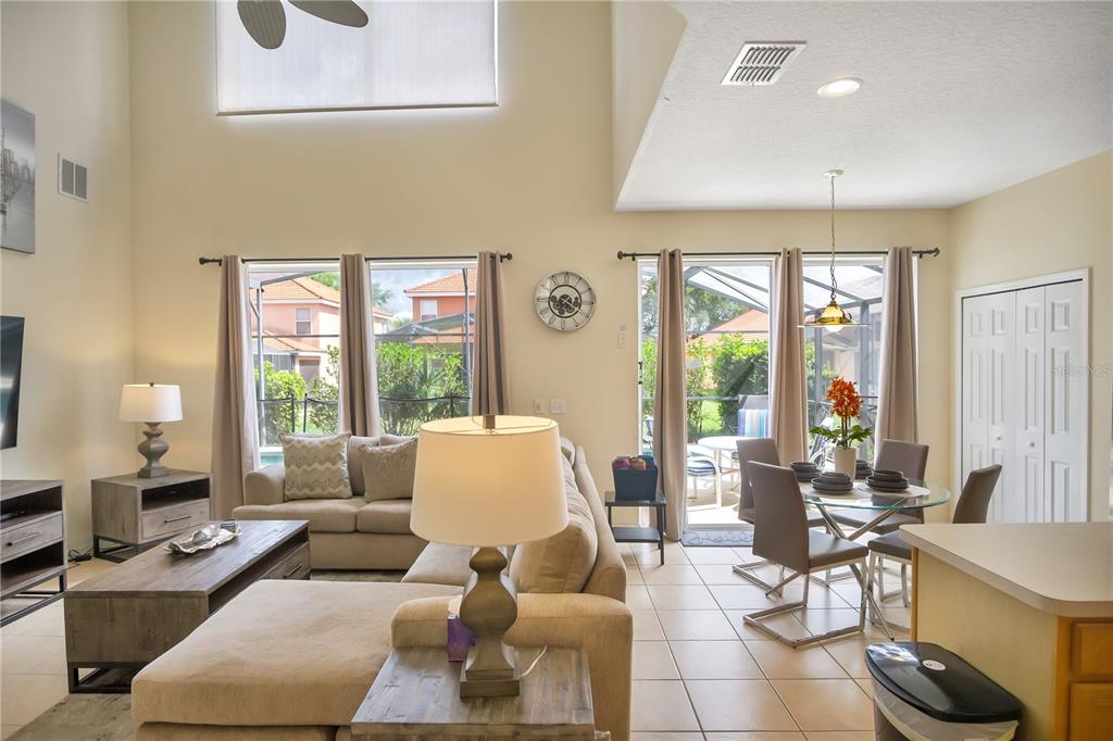 A living room and dining area with tile floors, vaulted ceilings, and a pool view — 134 SEVILLA AVENUE, DAVENPORT, FL