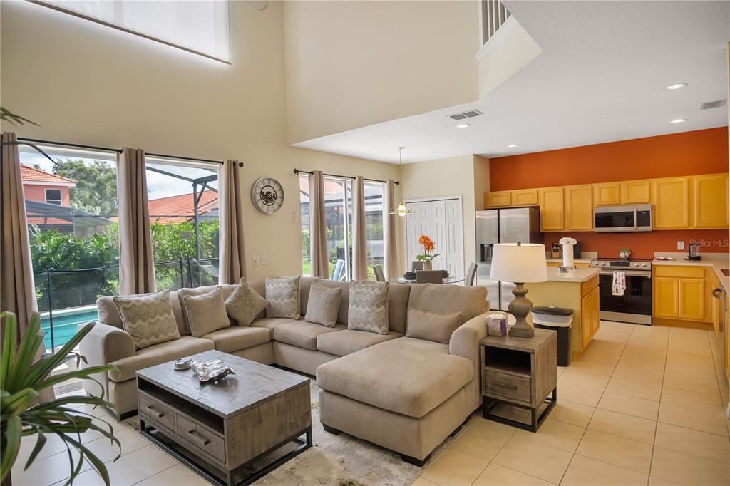 A living and dining area with high ceilings, tile floors, and sliding glass doors to a patio — 134 SEVILLA AVENUE, DAVENPORT, FL