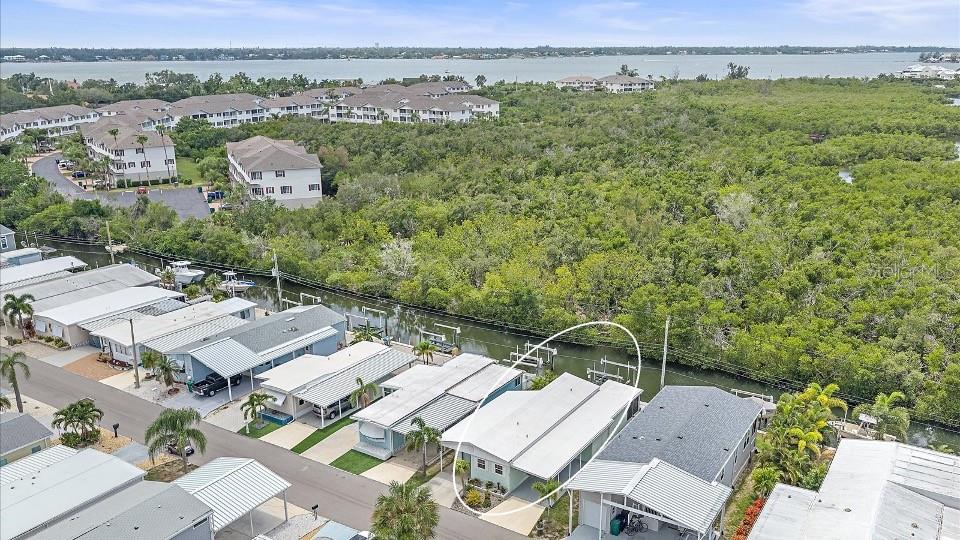 An aerial view shows a light-colored mobile home with a carport along a canal — 192 BIMINI DRIVE, PALMETTO, FL